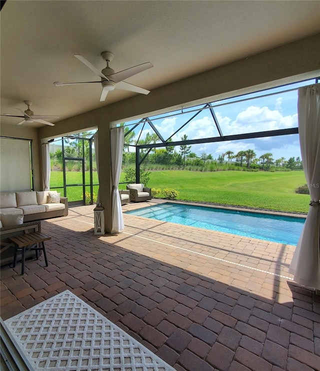 view of swimming pool with a patio, a lawn, ceiling fan, and glass enclosure