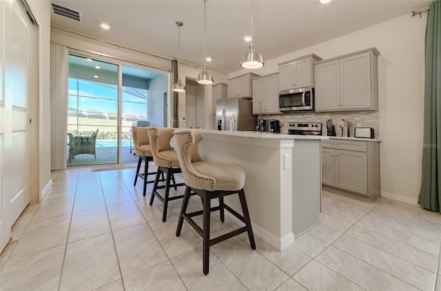 kitchen featuring gray cabinetry, pendant lighting, a center island with sink, and stainless steel appliances