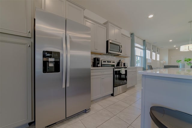 kitchen with decorative backsplash, light tile patterned floors, decorative light fixtures, and appliances with stainless steel finishes