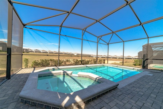 view of swimming pool featuring an in ground hot tub, a patio, and glass enclosure