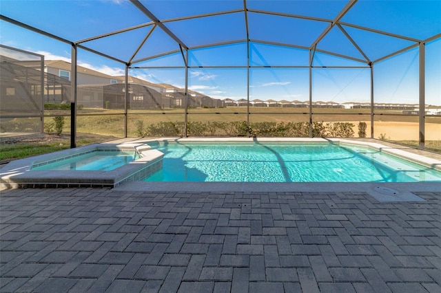 view of pool with glass enclosure, a patio area, and an in ground hot tub