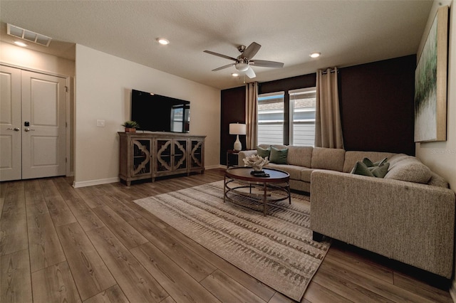 living room with ceiling fan, hardwood / wood-style floors, and a textured ceiling