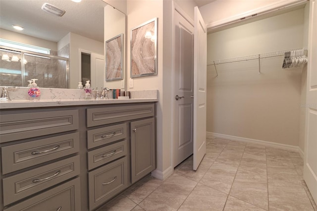 1166 Aloha Blvd, Davenport, FL 33897 - bathroom with double vanity, a shower stall, a walk in closet, and a textured ceiling