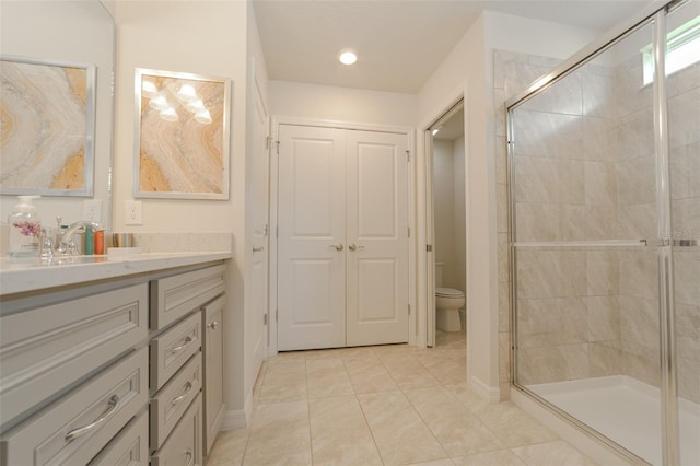 bathroom with tile patterned floors, vanity, a shower with shower door, and toilet