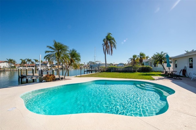 view of swimming pool featuring a patio area, a water view, a yard, and a dock