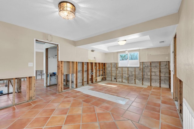 tiled spare room featuring a tray ceiling