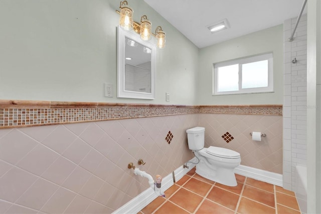 bathroom with tile patterned flooring, toilet, and tile walls