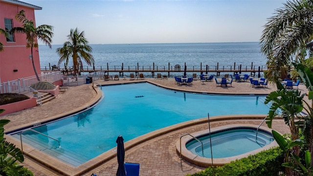 view of pool featuring a water view and a hot tub