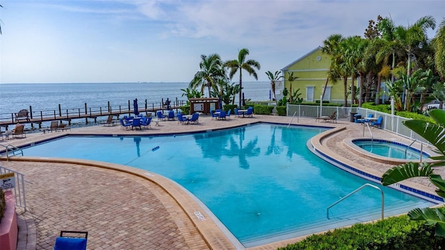 view of swimming pool with a patio area, a community hot tub, and a water view