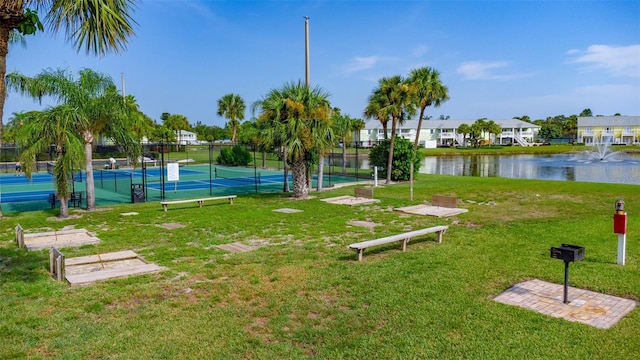 view of home's community with a lawn, a water view, and tennis court