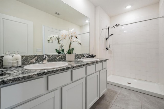 bathroom featuring tile patterned flooring, vanity, and tiled shower