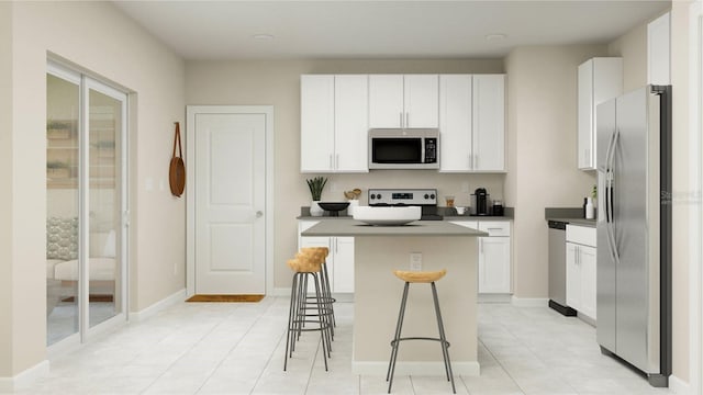 kitchen featuring stainless steel appliances, light tile patterned floors, a kitchen island, a breakfast bar, and white cabinets