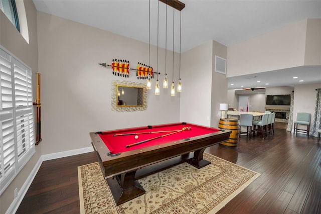 game room featuring dark wood-type flooring, a towering ceiling, a stone fireplace, and billiards