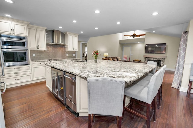 kitchen featuring a spacious island, wall chimney exhaust hood, and a breakfast bar area