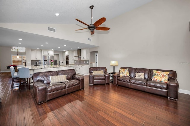 living room with dark wood-type flooring, ceiling fan, vaulted ceiling, and sink