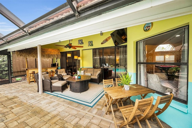 exterior space with an outdoor hangout area, ceiling fan, and glass enclosure