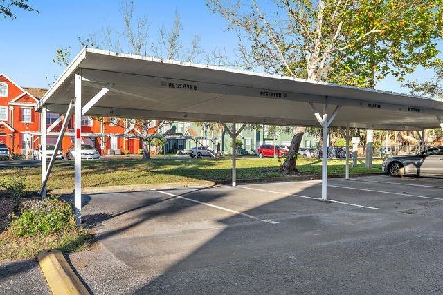 view of parking / parking lot with a lawn and a carport