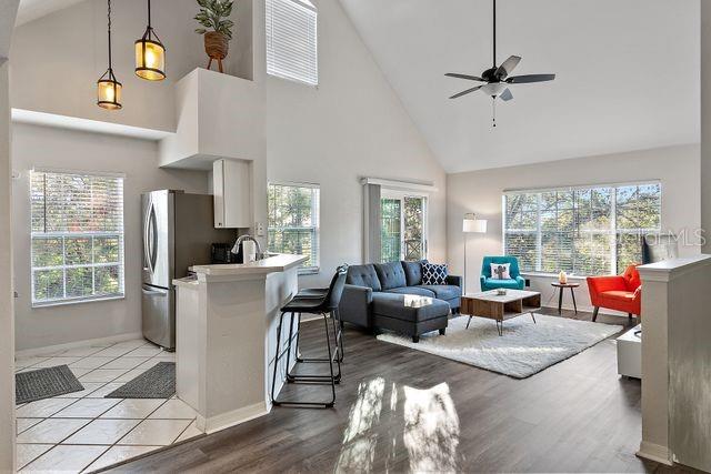 living room with a towering ceiling, light hardwood / wood-style floors, and ceiling fan