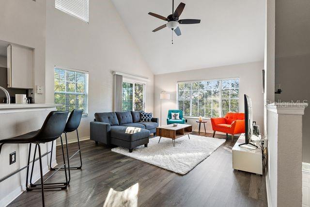 living room with plenty of natural light, ceiling fan, dark hardwood / wood-style floors, and high vaulted ceiling