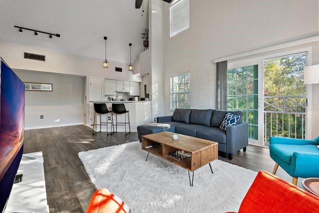 living room featuring a high ceiling, track lighting, ceiling fan, and dark wood-type flooring