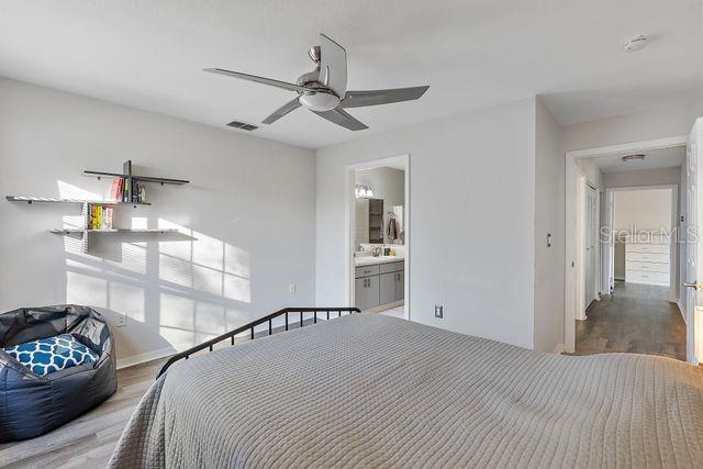 bedroom with wood-type flooring, ensuite bathroom, and ceiling fan