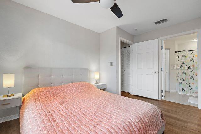 bedroom featuring dark hardwood / wood-style floors, ceiling fan, and ensuite bathroom