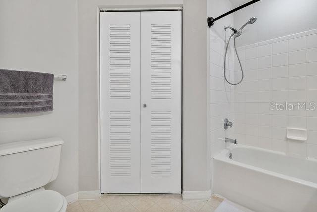 bathroom featuring tiled shower / bath combo and toilet