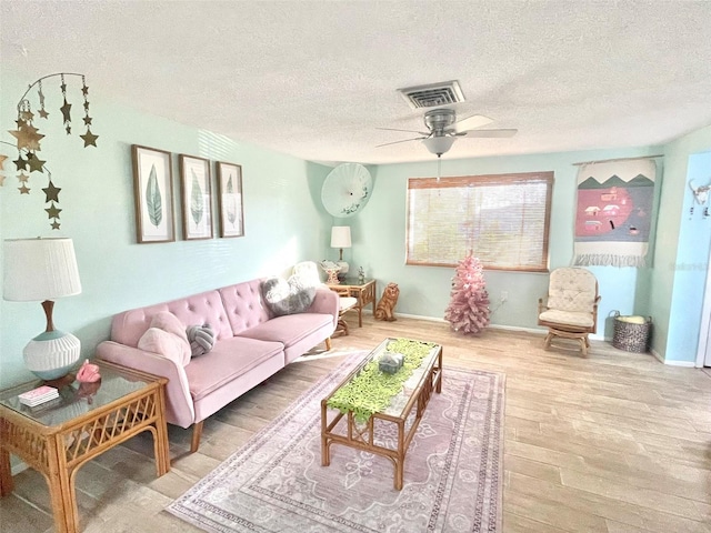 living room featuring hardwood / wood-style floors, ceiling fan, and a textured ceiling