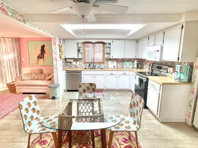 kitchen featuring white cabinets, stainless steel appliances, a tray ceiling, and sink