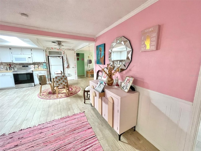 interior space with ceiling fan, a textured ceiling, white appliances, white cabinets, and light wood-type flooring