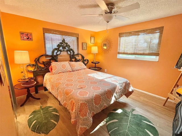 bedroom featuring ceiling fan, a textured ceiling, and light wood-type flooring