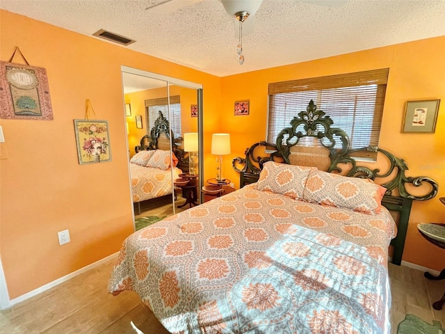 bedroom with ceiling fan, a closet, a textured ceiling, and light hardwood / wood-style flooring