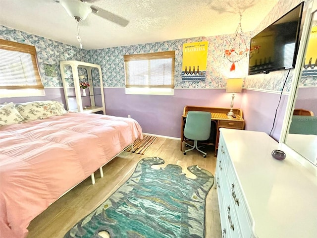 bedroom with ceiling fan, light hardwood / wood-style flooring, and a textured ceiling