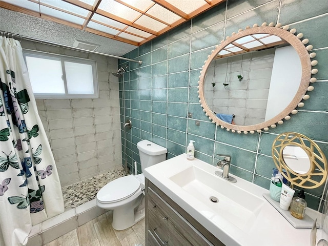 bathroom with vanity, wood-type flooring, tile walls, toilet, and curtained shower