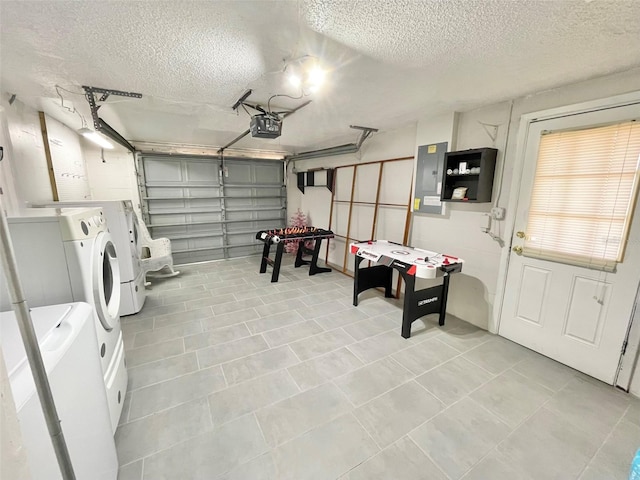 garage featuring electric panel, a garage door opener, and independent washer and dryer