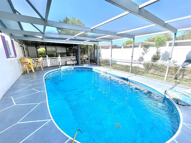 view of swimming pool featuring glass enclosure