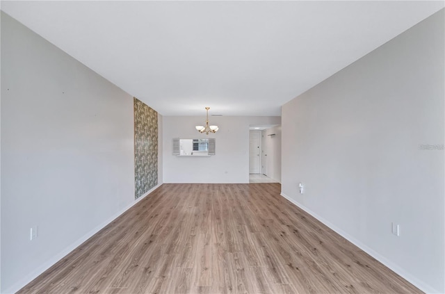 unfurnished living room featuring light wood-type flooring and an inviting chandelier