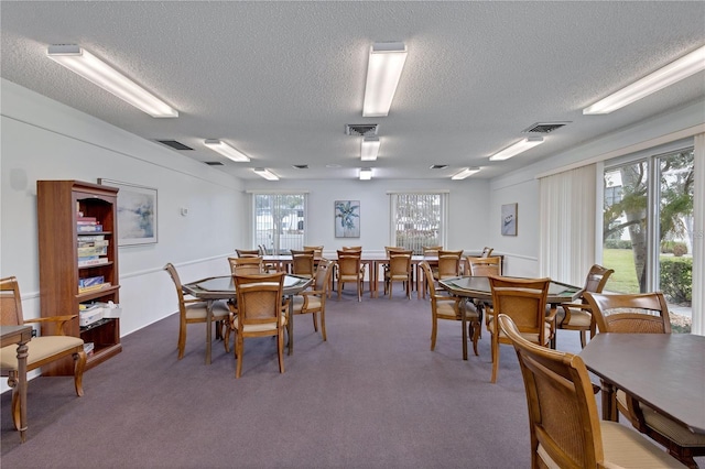 dining area featuring dark colored carpet and a textured ceiling