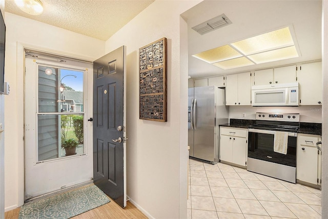 kitchen featuring white cabinetry, light tile patterned floors, stainless steel appliances, and a textured ceiling