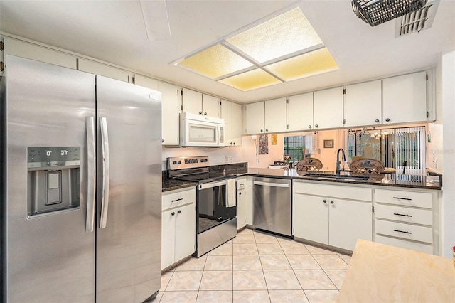 kitchen featuring sink, white cabinets, stainless steel appliances, and light tile patterned floors