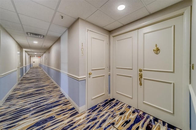 corridor featuring carpet flooring and a drop ceiling