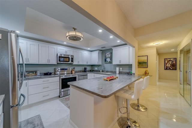 kitchen with white cabinets, kitchen peninsula, stainless steel appliances, and a breakfast bar area