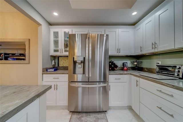 kitchen featuring white cabinetry, stainless steel fridge with ice dispenser, light tile patterned floors, and light stone countertops