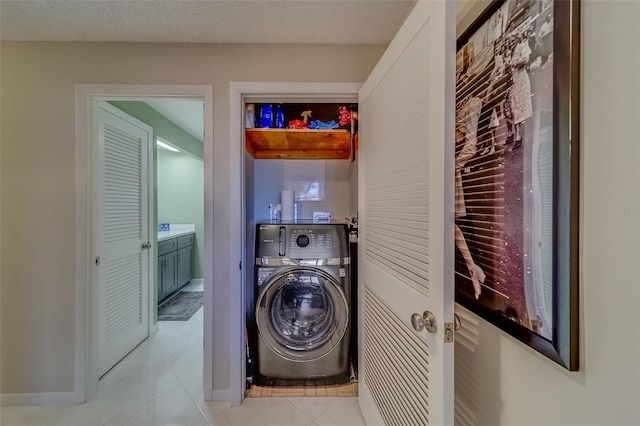 clothes washing area with washer / dryer, light tile patterned floors, and a textured ceiling