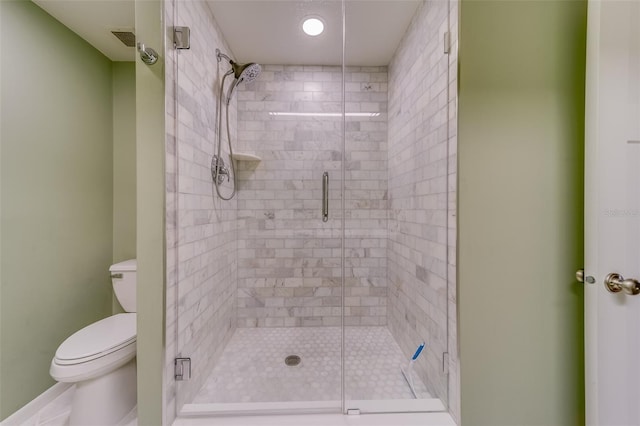 bathroom with tile patterned floors, toilet, and a shower with door