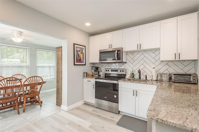 kitchen featuring appliances with stainless steel finishes, tasteful backsplash, ceiling fan, sink, and white cabinets