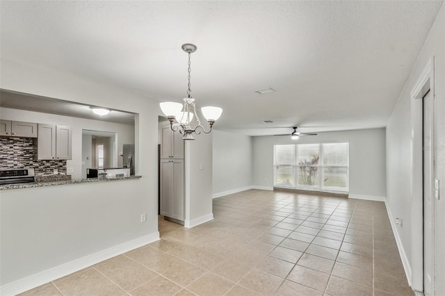 unfurnished dining area with light tile patterned floors and ceiling fan with notable chandelier