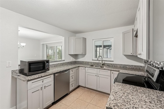 kitchen with light stone countertops, sink, an inviting chandelier, a textured ceiling, and appliances with stainless steel finishes