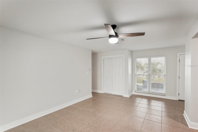 tiled spare room featuring ceiling fan