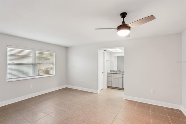 tiled empty room featuring ceiling fan and sink